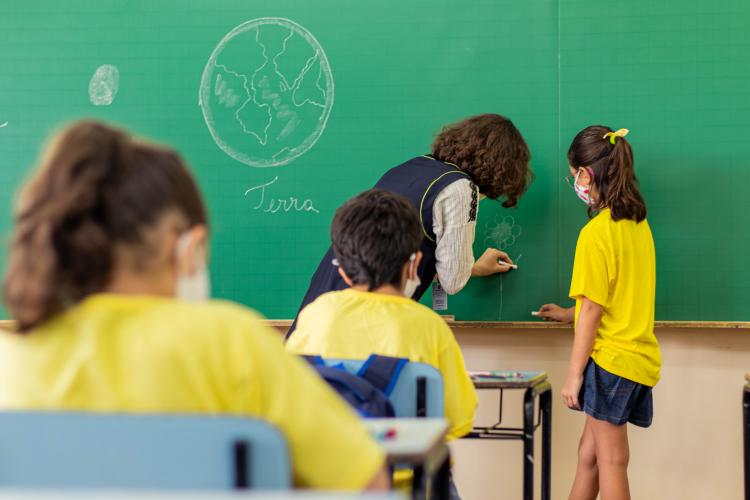 Foto de sala de aula com alunos e professora.